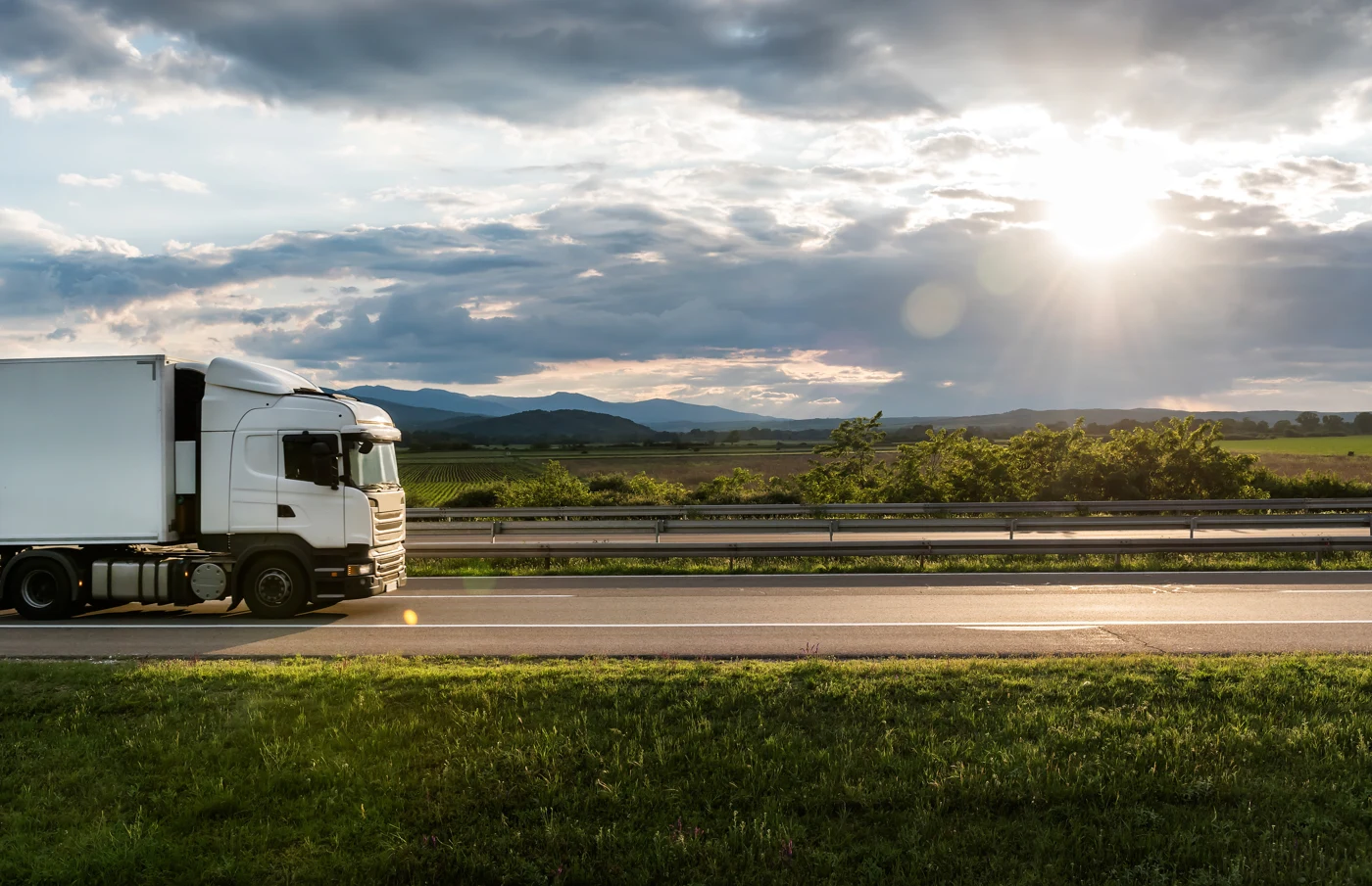 Truck travelling through an open landscape at sunset